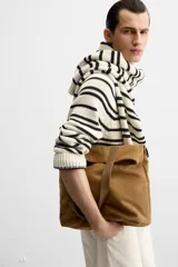 Bolso tipo shopper color marrón claro, fabricado en cuero con acabado serraje. Tiene doble asa de mano de cuero y un bolsillo interior con cierre.