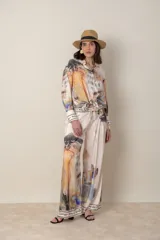Pantalón palazzo italiano de satén de seda color natural con estampado en tonos de verde, lila y naranja. Cintura con elástico y cordón, bolsillos laterales. Cintura y bajo con guarda escrita.
