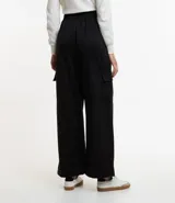 Pantalón largo negro de material sintético con cintura elástica, bolsillos laterales tipo cargo y abotonado delantero.
