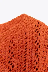 Top corto de punto color naranja, con cuello redondo amplio y manga corta.