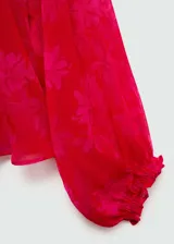 Blusa roja con estampado floral, de tejido fluido semitransparente y manga larga con puños elásticos. Tiene cuello redondo con cierre de lazo.