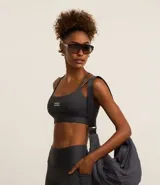 Top deportivo gris oscuro con breteles finos con lettering y estampa frontal con la palabra "Sporty".