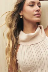 Top tejido de punto color beige, con cuello alto y diseño sin mangas.