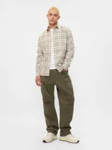 Camisa manga larga a cuadros beige, blanco y negro, con cuello abotonado y bolsillo en el pecho.