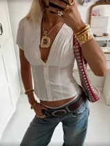 Camisa blanca entallada con cuello clásico, mangas cortas y cierre frontal con botones.