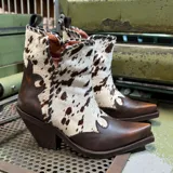 Bota corta de cuero marrón con apliques de cuero vacuno con manchas blancas y marrones. Tiene taco de madera y puntera cuadrada.