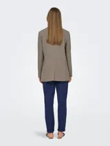Blazer largo color marrón topo, de corte holgado y tejido sastrero con trama twill. Tiene cuello con solapa y bolsillos delanteros funcionales.