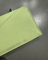 Sobre marrón de cuero sintético con cierre de solapa y costuras diagonales.