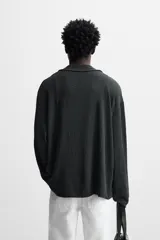 Camisa negra de manga larga con cuello bowling y cierre frontal con botones.