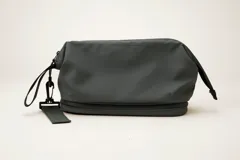 Neceser gris de poliéster con doble compartimento con cierre, asa lateral y logo de la marca estampado en el frente.