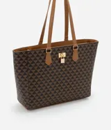 Bolso shopper grande de cuero sintético color marrón con estampado de triángulos negros. Tiene doble asa de mano color marrón, cierre superior con cremallera y detalle de candado decorativo dorado.