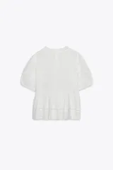 Blusa negra de algodón con cuello redondo y manga corta abullonada. Presenta bordados a tono y cierre en la espalda con abertura y botón.