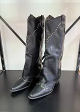 Botas texanas negras de caña alta con detalle de tachas doradas.