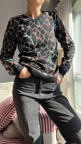 Sweater de punto con cuello en V y estampado abstracto en tonos negro, azul, rosa y verde.