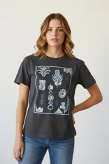 Remera de algodón color gris oscuro con cuello a la base y un estampado frontal de motivos florales y abstractos en tonos azules, plateados y dorados con lentejuelas.