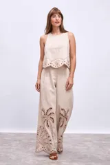 Pantalón de lino color beige con bordados de palmeras y conchas marinas en color marrón.
