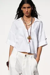 Camisa cropped color rosa de lino, con cuello solapa, escote pico, manga corta y bolsillos delanteros de plastrón.