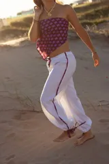 Pantalón blanco de lino 100% natural, con cordones regulables en los tobillos y detalles estampados en los costados.