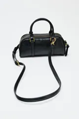 Bolso mini tipo bowling color negro, con doble compartimento con cierre de cremallera, asa de mano y asa bandolera extraíble.