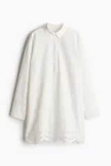 Vestido corto blanco de algodón con broderie, corte holgado, cuello camisero, tapeta con botones ocultos y mangas largas con puños abotonados. Bajo festoneado.
