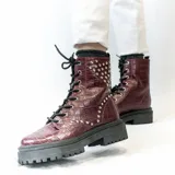 Bota de cuero negra con caña media, cordones y plataforma track. Presenta apliques de tachas plateadas en el lateral exterior.