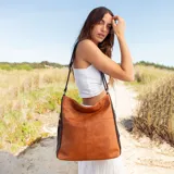 Cartera negra de simil cuero con apertura superior con cierre. Tiene detalle frontal en costura, dos bolsillos internos, un bolsillo divisor en el forro y bolsillos laterales con cierre. Incluye correa larga regulable.