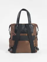 Mochila marrón de tela con detalles en cuero vegano negro, con doble asa de mano y correa de hombro ajustable.