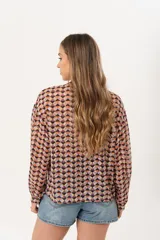 Camisa de gasa estampada traslúcida con diseño geométrico de rombos en tonos lila, naranja y negro. Tiene calce liviano y fluido, abotonado frontal y volado en la cartera.
