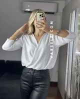 Blusa negra con estampado de lunares blancos, escote en V cruzado, mangas 3/4 abullonadas y hombreras. Talle único abarca hasta L.