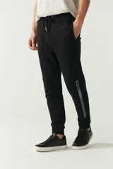 Pantalón de jogging negro de felpa con puños y cintura ajustable con cordón. Presenta logo de goma en la pierna izquierda y bolsillos laterales.