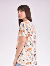 Remera estampada con motivos florales en tonos naranja, beige, gris y rosa.