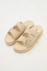 Sandalias bajas color beige con doble tira con hebilla y apliques de tachas.