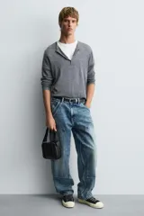 Bandolera negra acolchada con correa ajustable. Tiene un compartimento principal con cierre de cremallera, un bolsillo plano interior y tres compartimentos para tarjetas.