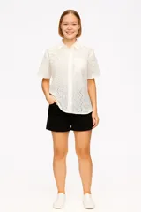 Camisa blanca de algodón con broderie, corte holgado, cuello camisero y mangas cortas.