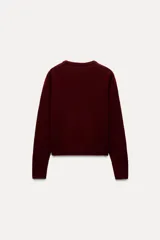 Jersey rojo de punto liso confeccionado en 100% lana. Tiene cuello redondo, manga larga y acabados en rib.