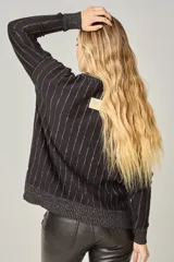 Sweater de punto negro con escote en V y rayas verticales plateadas.