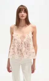 Top sin mangas de poliéster, color crema con estampado floral en tonos rosados. Presenta escote en V con volados en cascada y tirantes finos.
