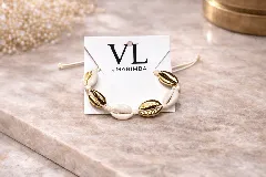 Pulsera con caracoles naturales y caracoles metalizados dorados, unidos por un cordón de hilo trenzado color crudo.