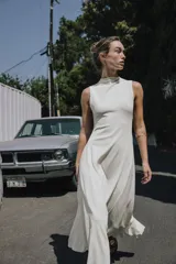 Vestido largo color blanco, de cuello redondo y sin mangas. Tejido con textura y corte evasé con vuelo.