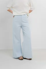 Pantalón de tiro alto, corte palazzo amplio y fluido, color celeste claro. Presenta bolsillos delanteros y traseros tipo jean, con logo metálico Peach en la parte posterior.