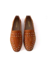 Mocasín de gamuza color terracota con detalle de tachas metálicas.