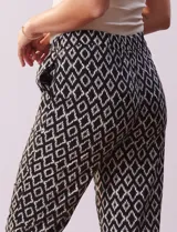 Pantalón negro con estampado geométrico blanco, de corte recto, con pretina ancha elastizada y lazo de ajuste.
