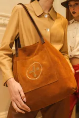 Bolso tipo tote bag de gamuza azul con asas de cuero marrón y bolsillo externo con logo bordado.