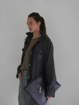 Camisa gris de lana con corte clásico, cuello camisero, cierre frontal con botones de cuerno y dos bolsillos de parche en el pecho.