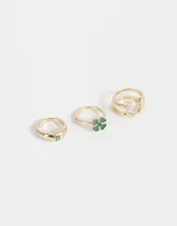 Set de tres anillos dorados con motivos de la buena suerte: uno con tréboles esmaltados, otro con trébol de resina y el tercero con una herradura de metal.