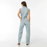 Mono largo de jean celeste, sin mangas, con cuello camisero, cierre frontal con botones, bolsillos delanteros y traseros, y cinturón con hebilla metálica.