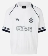 Camisa polo de punto color blanco con rayas azul marino en cuello y mangas. Tiene bordados localizados y lettering.