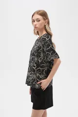 Blusa verde militar con estampado de flores blancas, de viscosa, corte holgado, cuello redondo y mangas cortas.