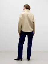 Camisa beige de algodón con cuello chimenea y cierre lateral con cuatro broches a presión. Manga japonesa con corte en la sisa en la espalda y puño con abertura y broche.