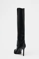 Bota alta de cuero negro con puntera fina y tacón de aguja. Diseño estilo cowboy con paneles combinados de cuero liso y gamuza.